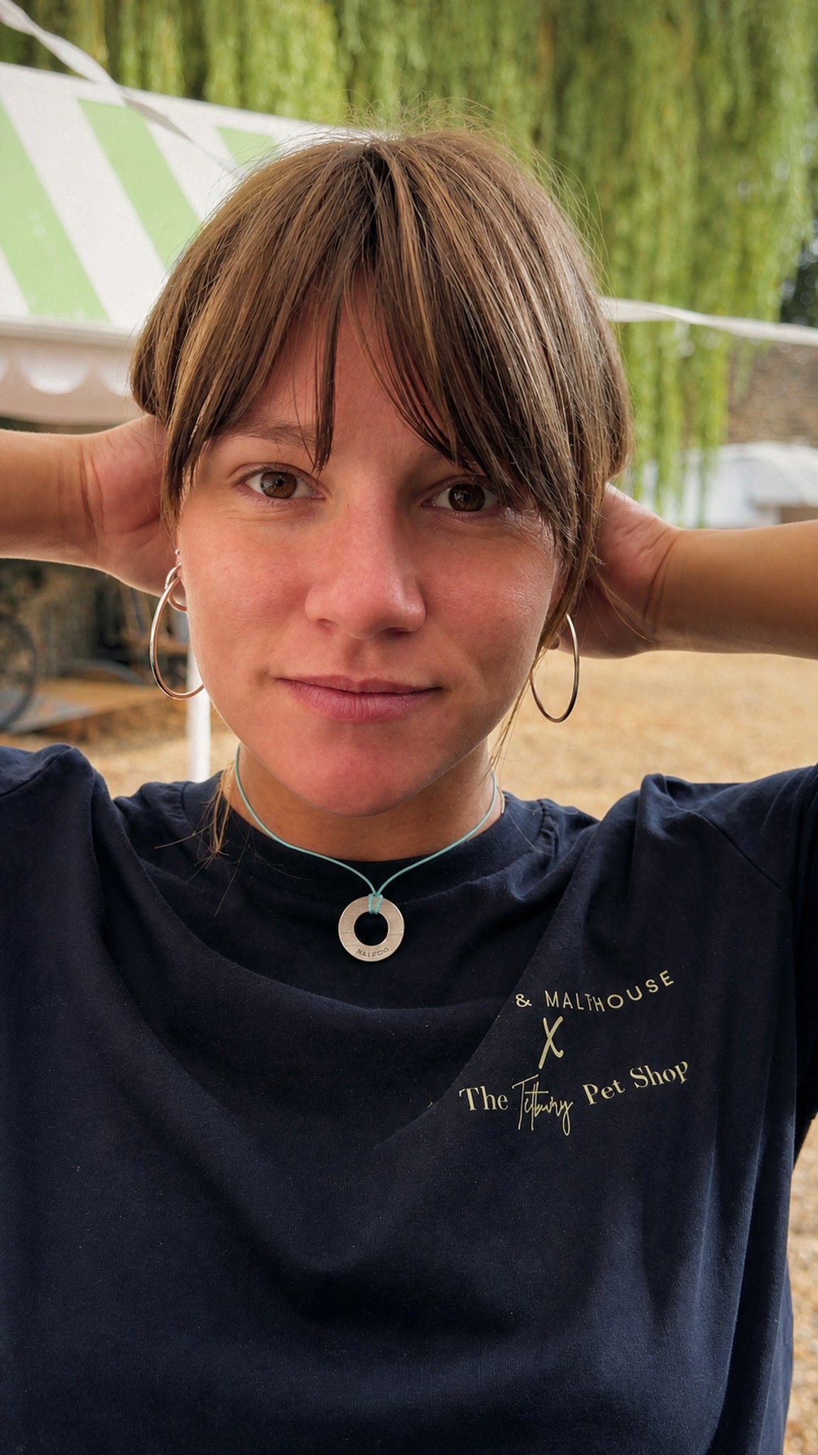 Close-up of a woman wearing an engraved brass Bondlets pendant with her dog's name