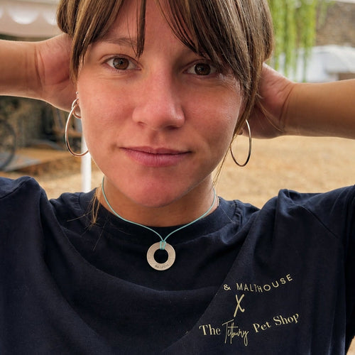 Close-up of a woman wearing an engraved brass Bondlets pendant with her dog's name