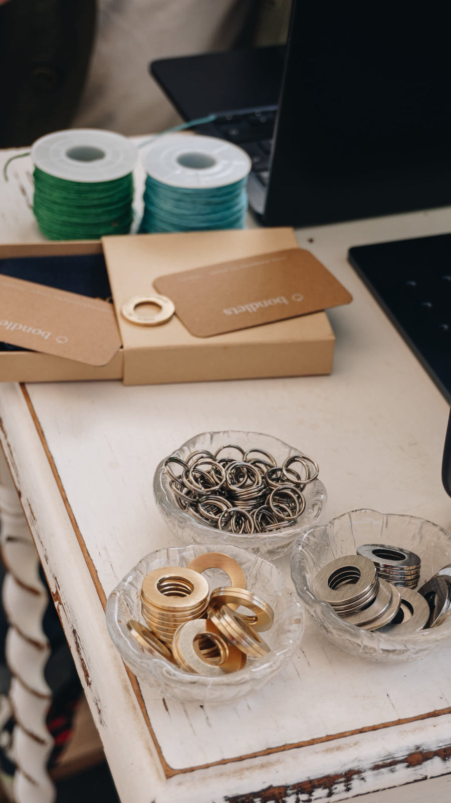 Brass and stainless steel Bondlets discs in glass bowls on the engraving bench in Tetbury
