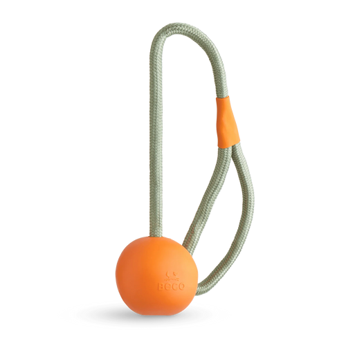The Beco Slinger by The Tetbury Pet Shop & Grooming is an orange natural rubber fetch ball on a gray rope loop with an orange grip, designed for fun, interactive play with your dog.