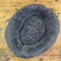 Round grey fluffy pet bed on a wooden floor