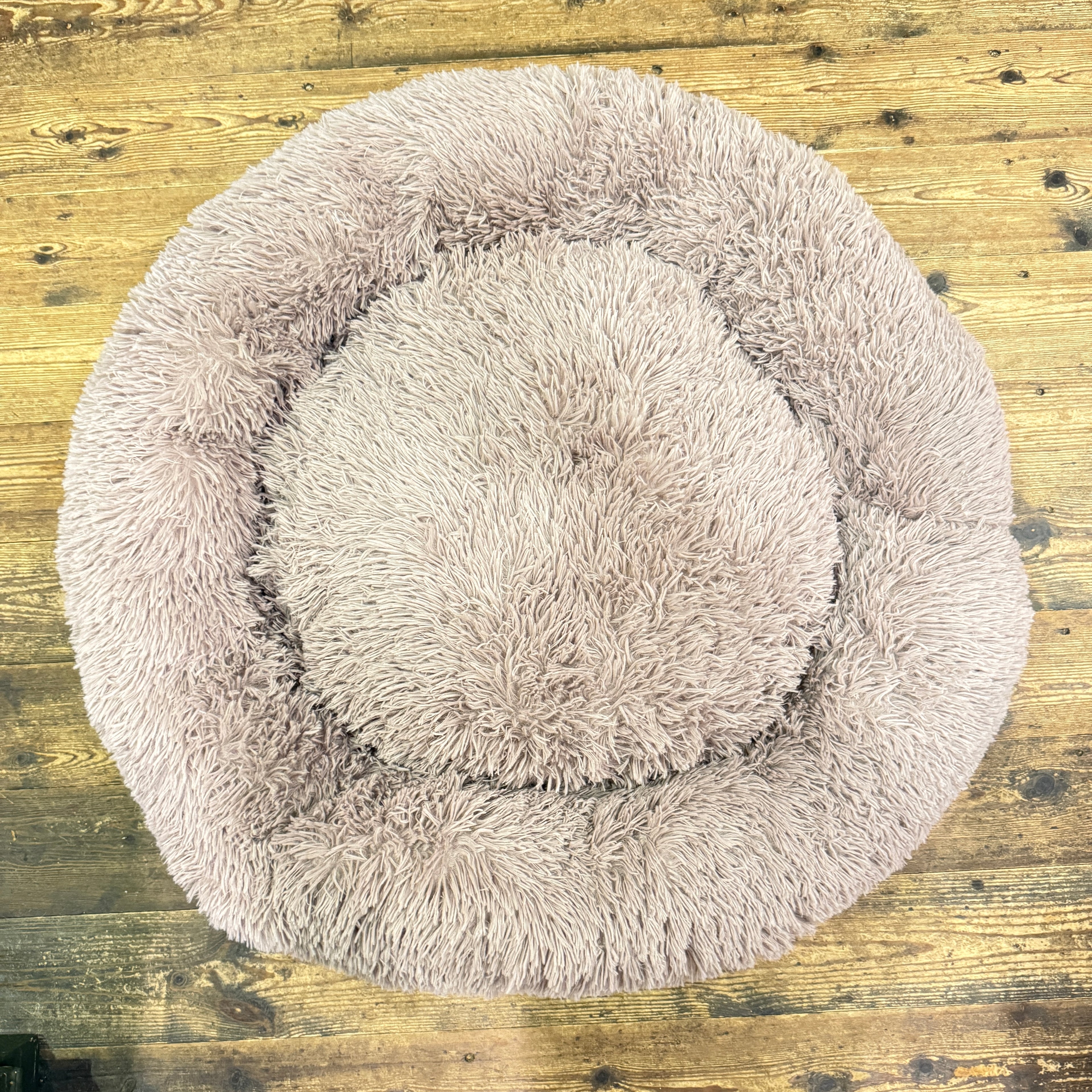 Round fluffy pet bed on a wooden floor