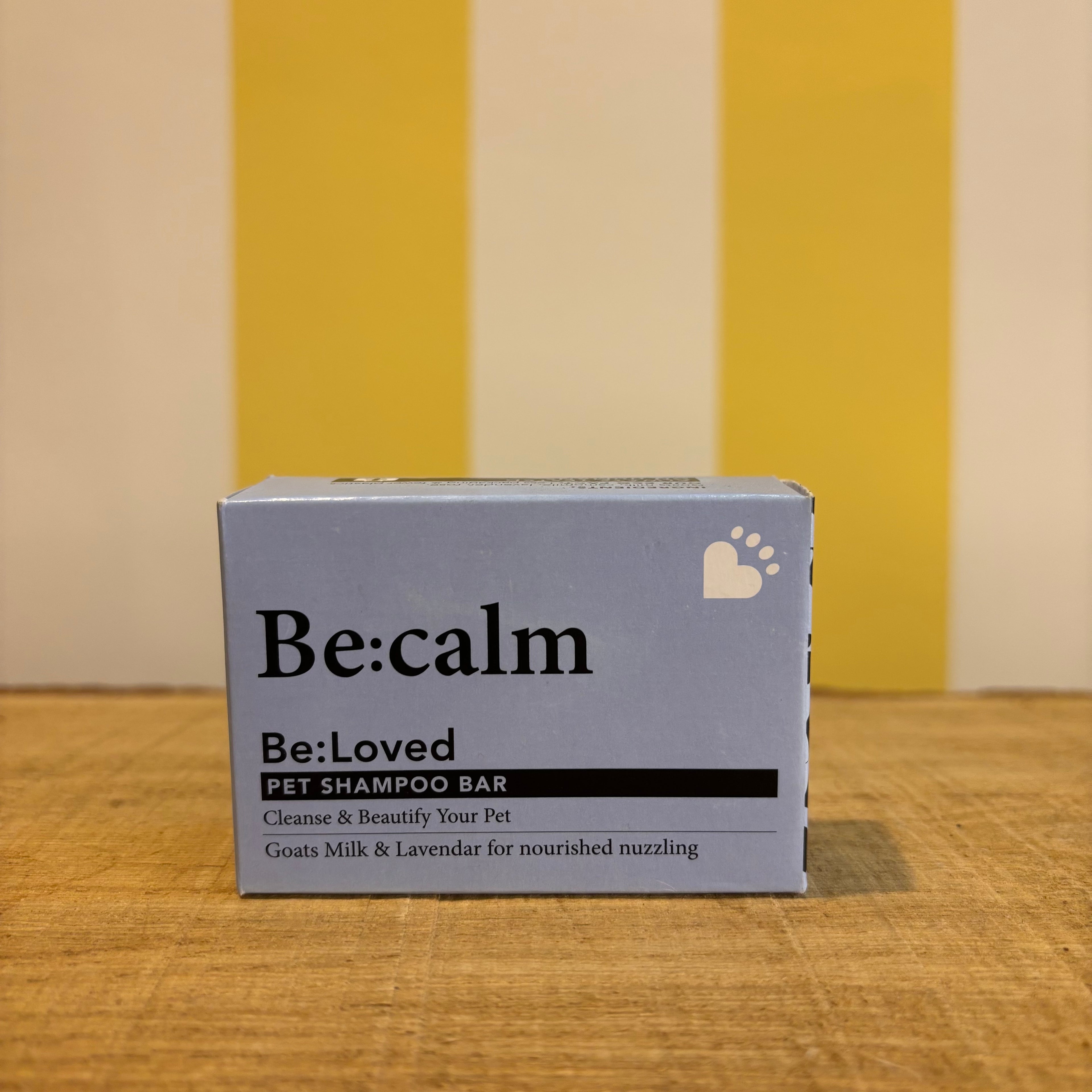 Three boxes of The Tetbury Pet Shop & Grooming's Be: Natural Shampoo Bars are stacked on wood with a yellow and white striped background, showcasing these eco-friendly pet shampoos.