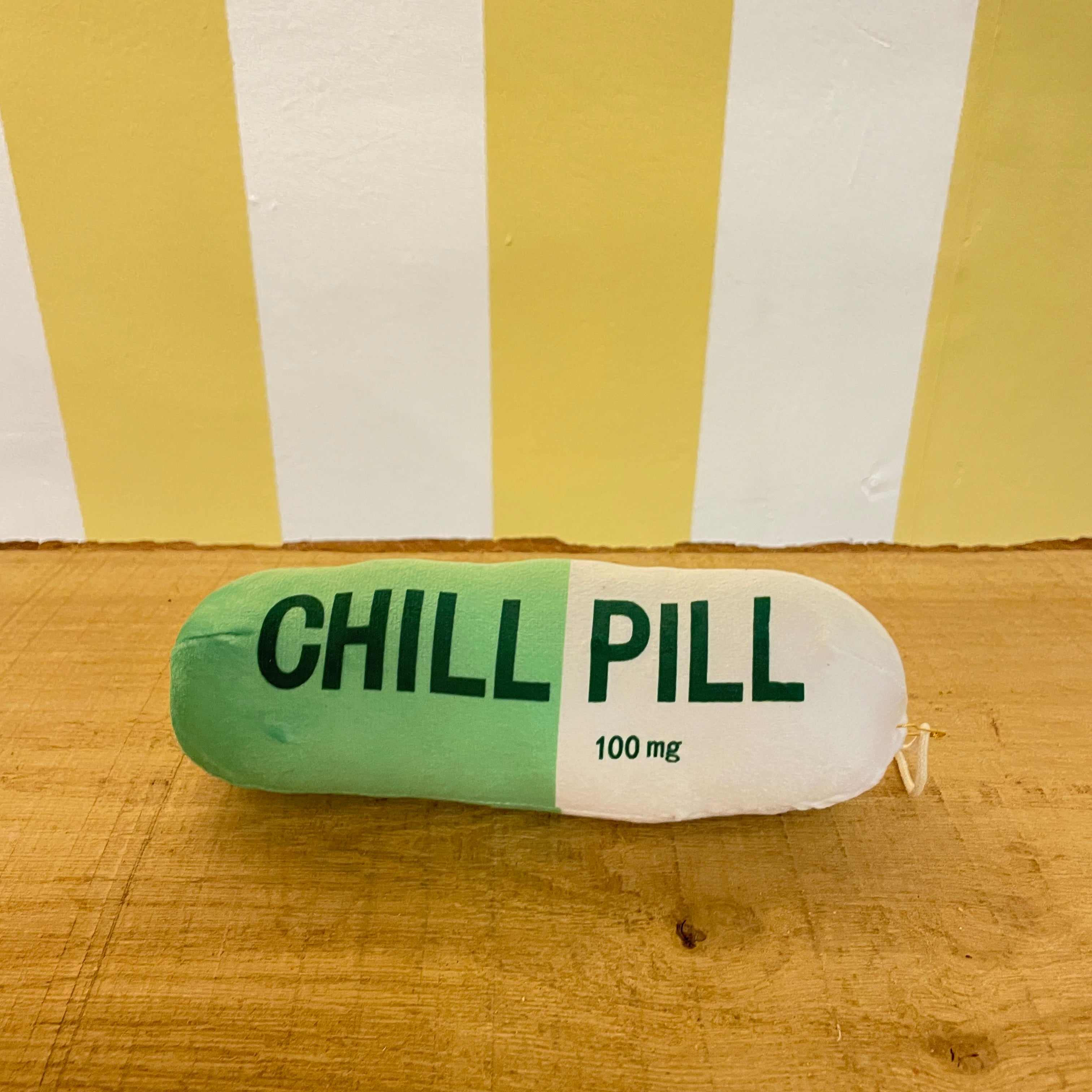 The Tetbury Pet Shop & Grooming's Chill Pill is a plush green and white capsule toy for dogs, labeled "CHILL PILL" and hanging from a clip—perfect as a quirky squeaky toy for your pup.