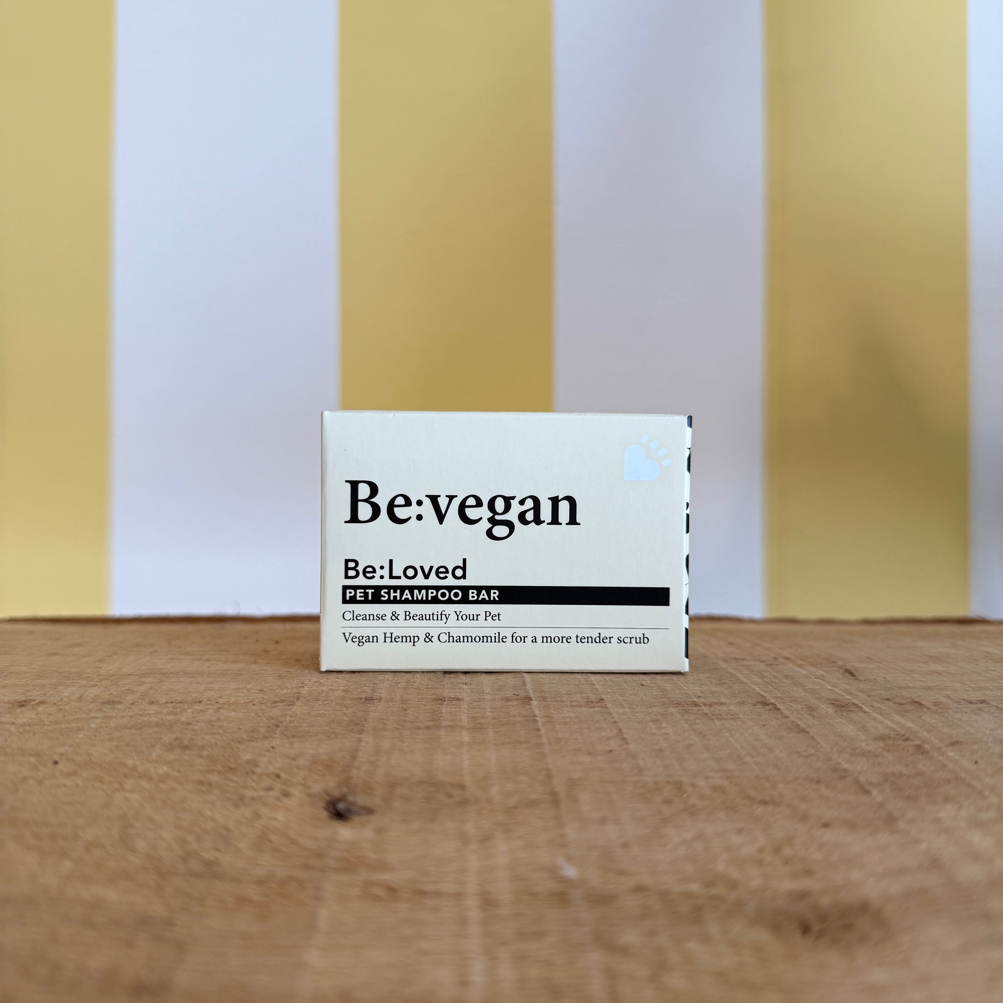 Three boxes of The Tetbury Pet Shop & Grooming's Be: Natural Shampoo Bars are stacked on wood with a yellow and white striped background, showcasing these eco-friendly pet shampoos.