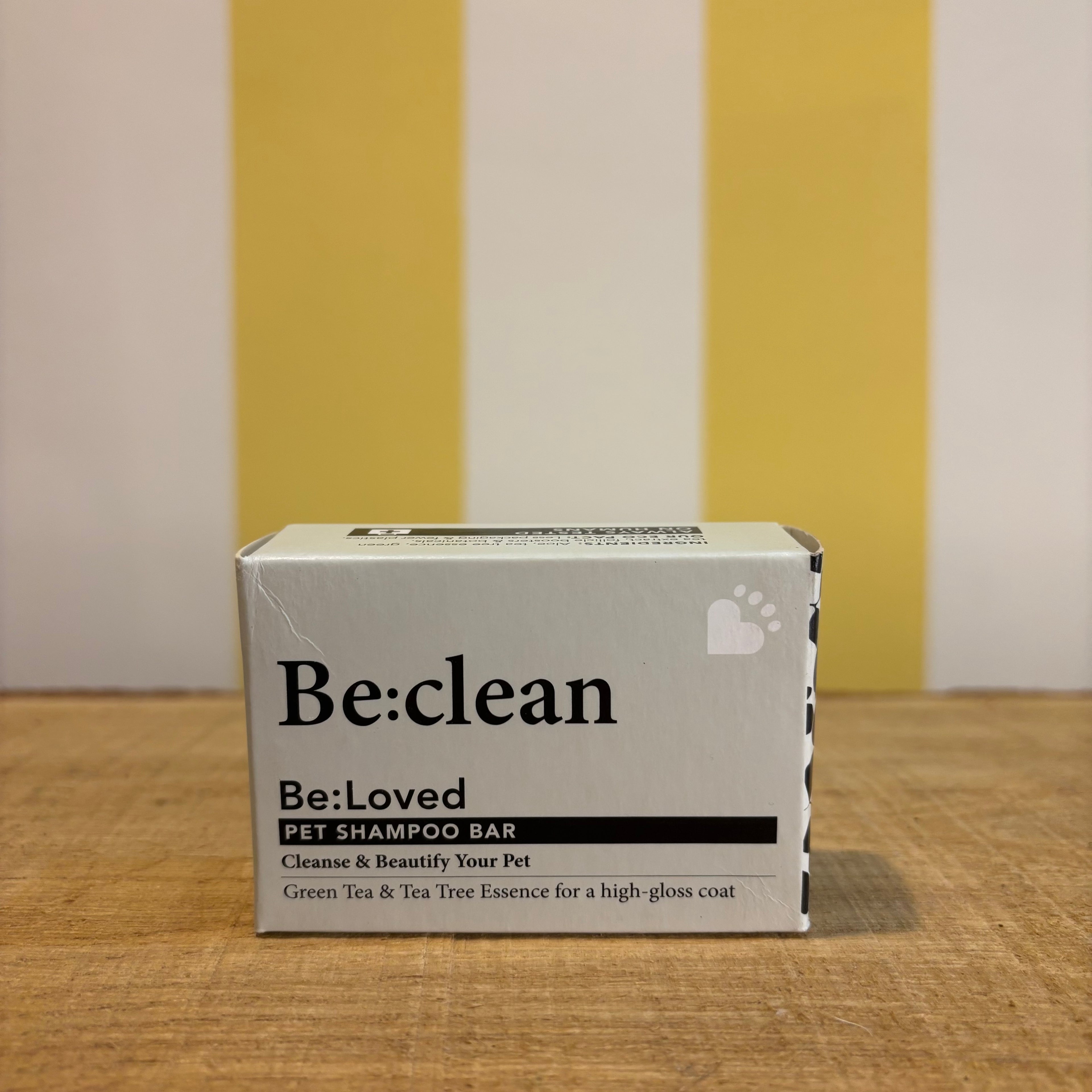 Three boxes of The Tetbury Pet Shop & Grooming's Be: Natural Shampoo Bars are stacked on wood with a yellow and white striped background, showcasing these eco-friendly pet shampoos.