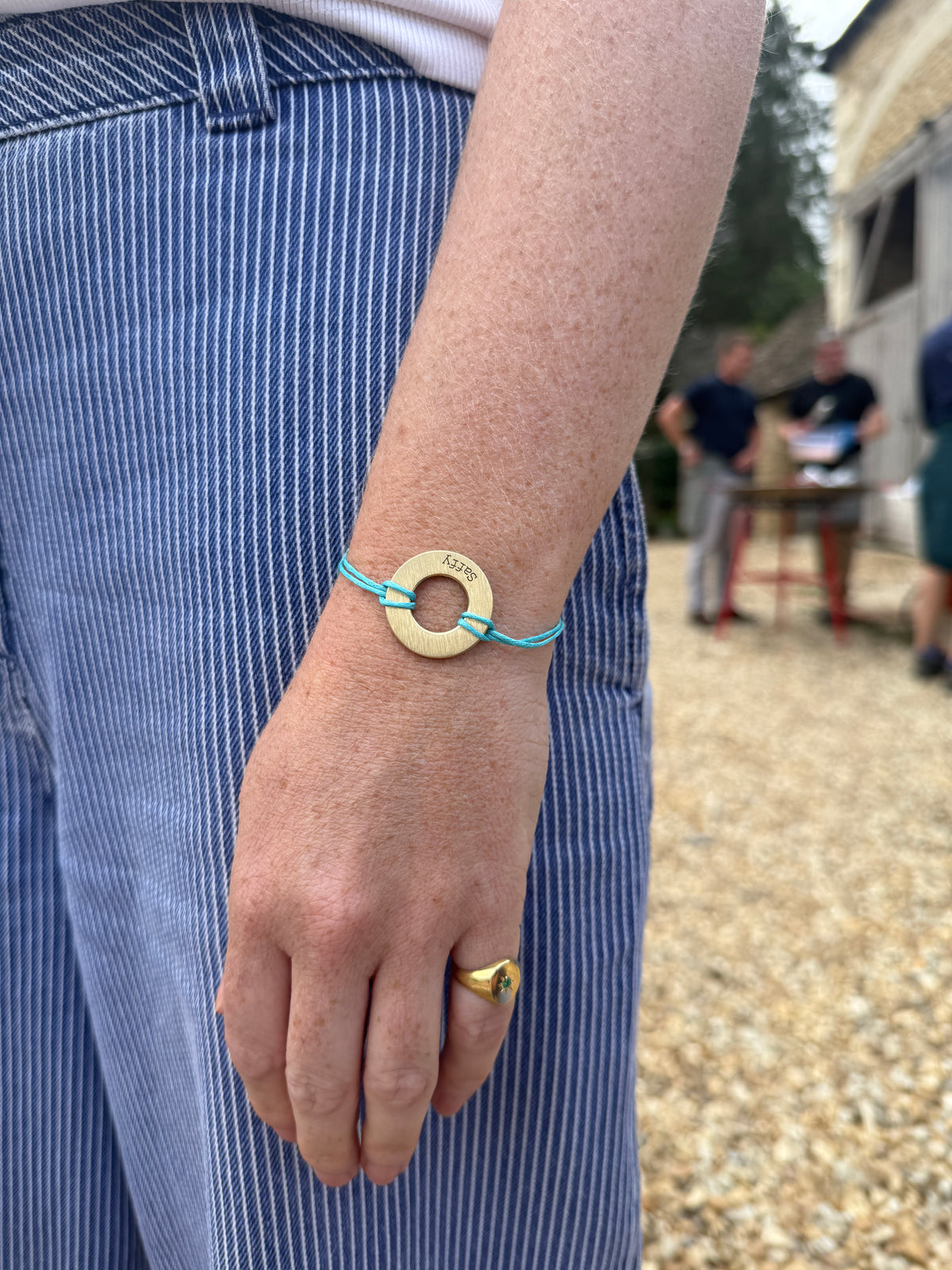 Brass Bondlets disc engraved with the name Saffy, worn as a bracelet on a turquoise cord
