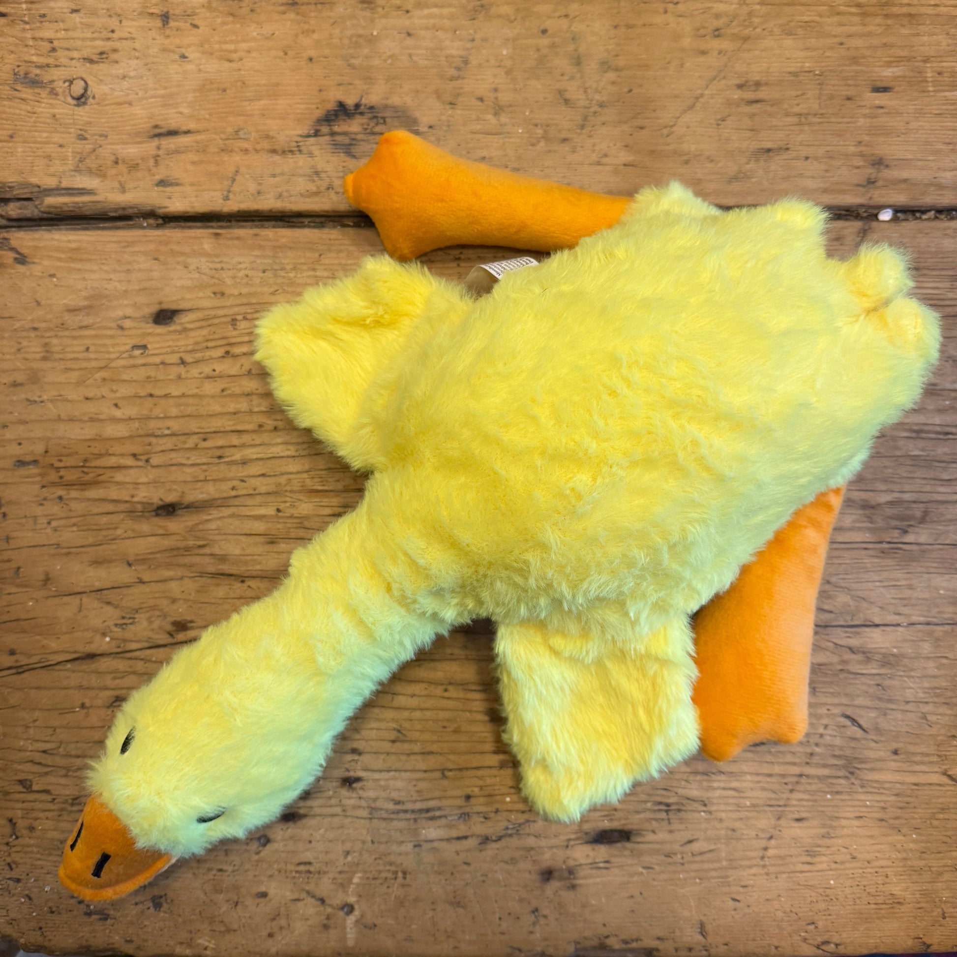 Yellow plush duck toy on a wooden surface