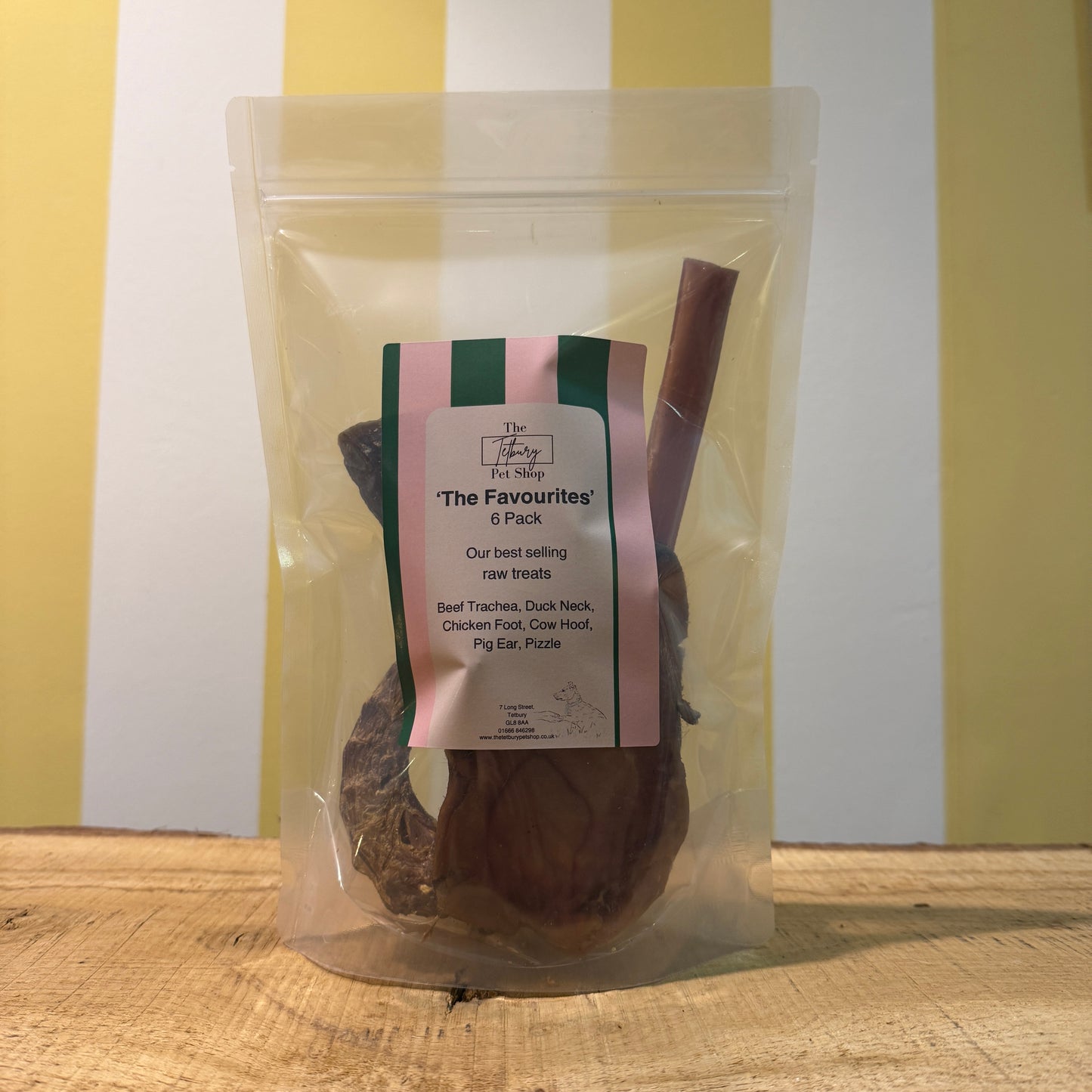 A packaged variety pack of raw dog treats, visible through the clear plastic, with a label showing different treats inside like beef trachea, duck neck, chicken foot, cow hoof, pig ear, and pizzle.